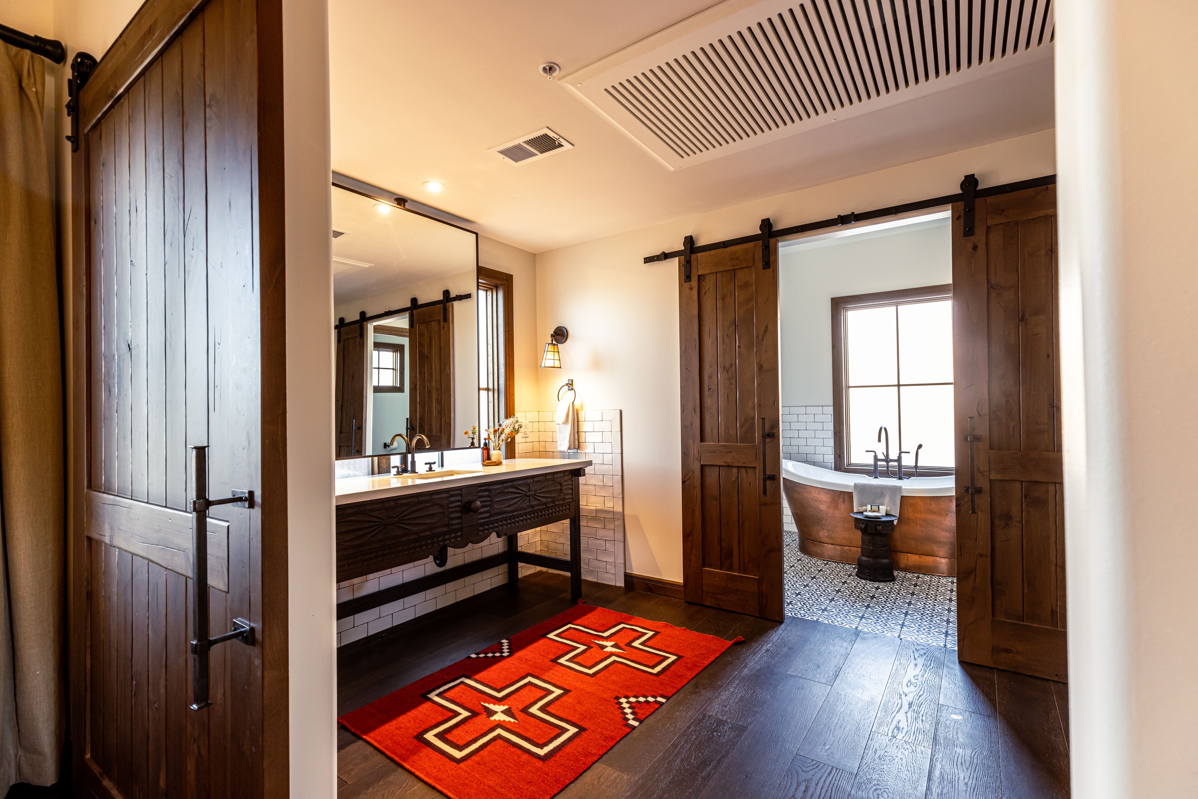Un bagno con porta in legno, un lavandino, uno specchio e una vasca da bagno.