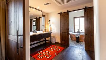 Un bagno con porta in legno, un lavandino, uno specchio e una vasca da bagno.