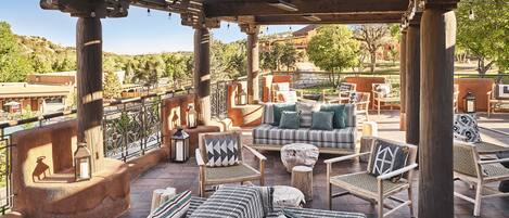 An outdoor patio with wooden furniture, a view of the surrounding landscape, and a pergola structure.
