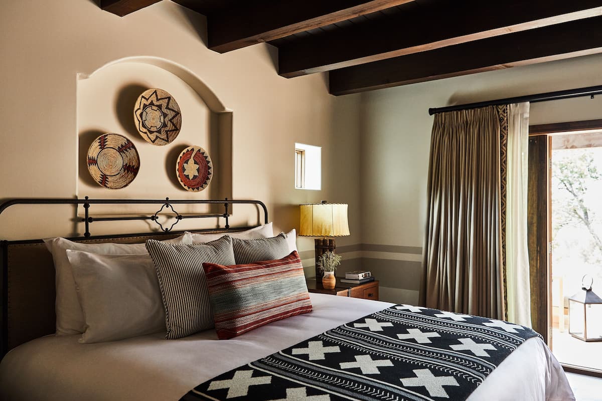 A neatly made bed with a patterned blanket, a bedside lamp, and decorative plates on the wall.