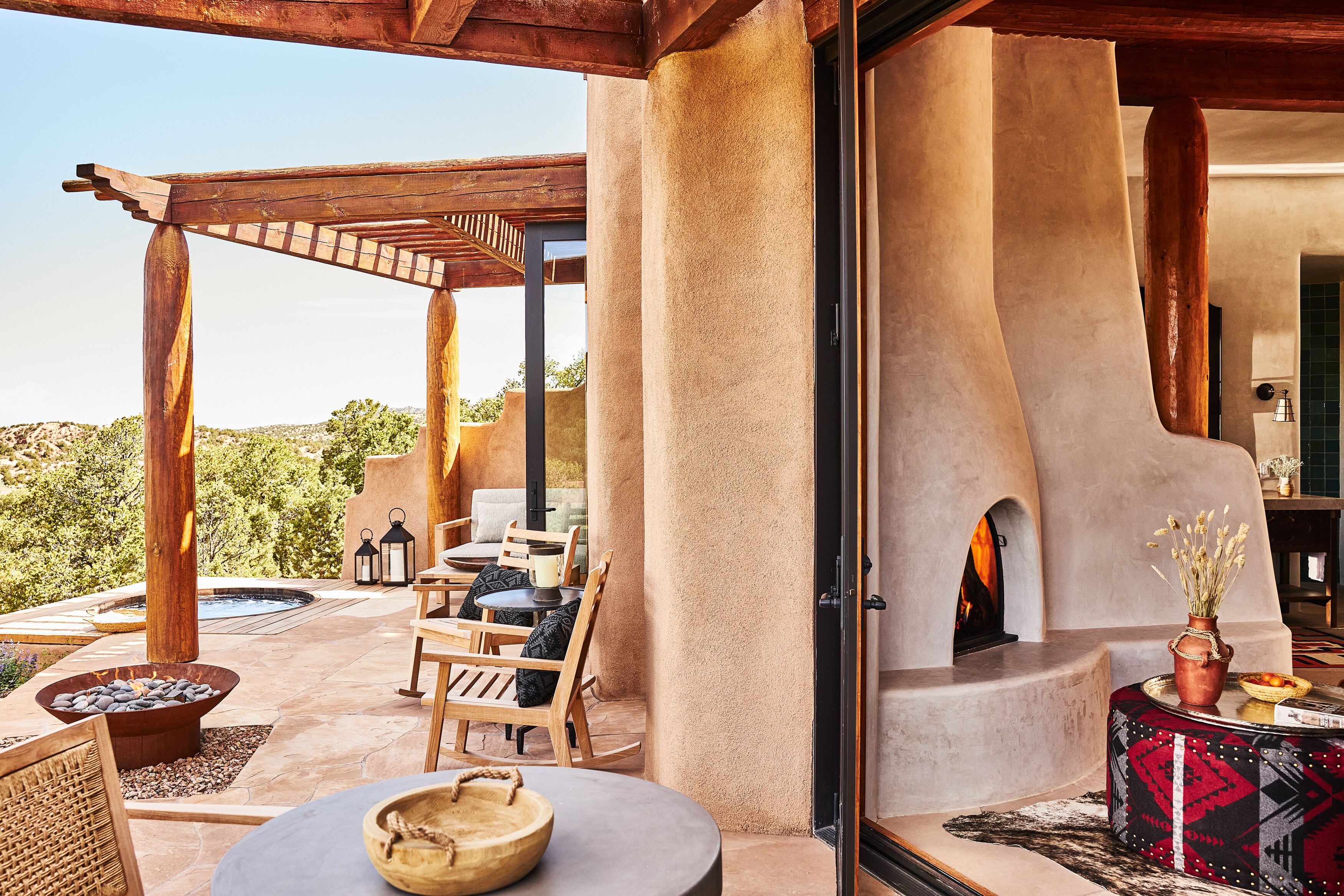 An outdoor patio with a wooden pergola, seating area, and a fire pit.
