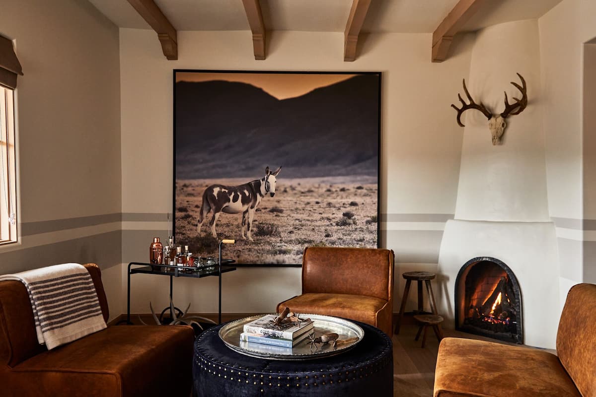A cozy living room with a fireplace, a large painting of a horse, and leather furniture.