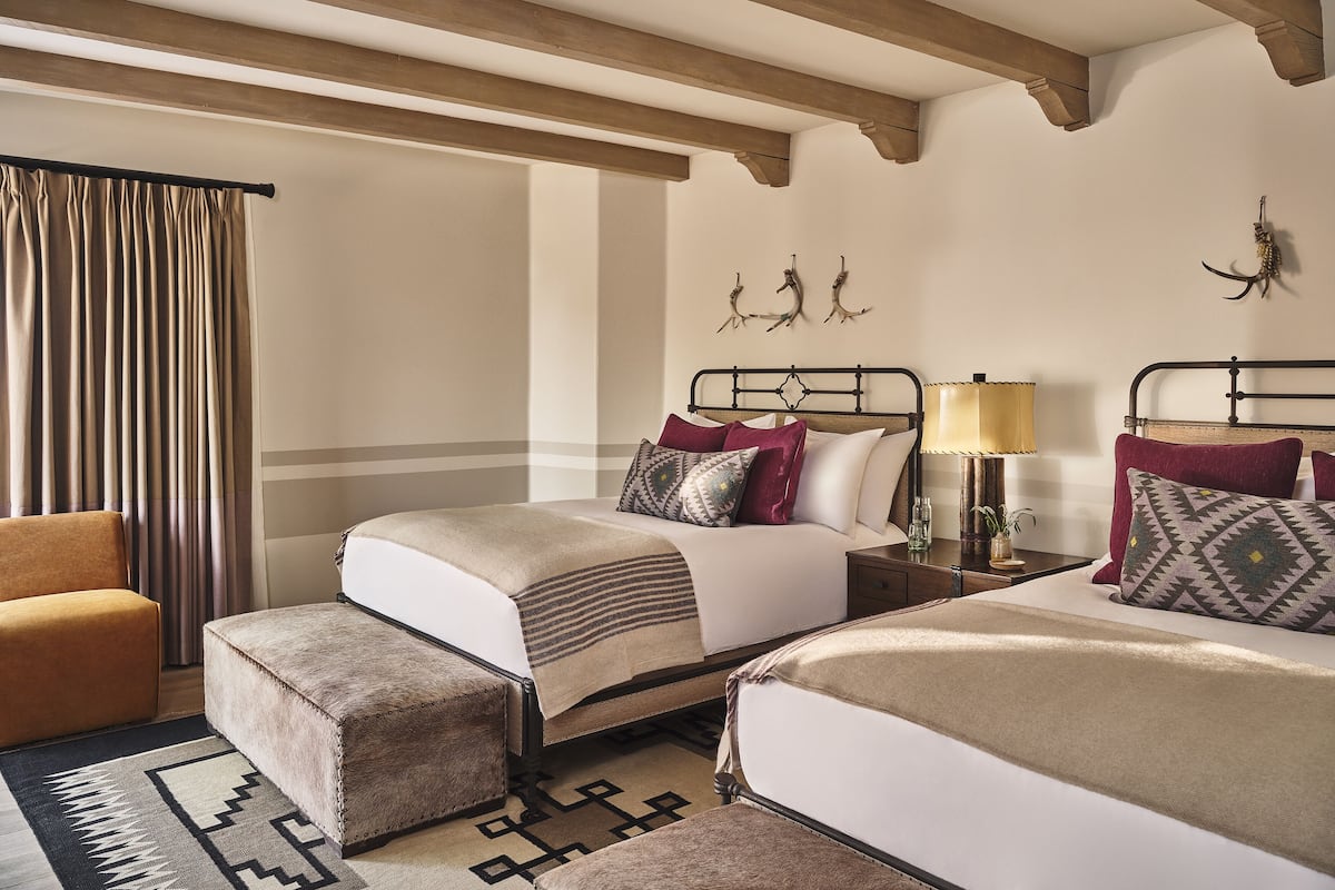 A hotel room with two beds, a sofa, a small table, and a lamp.