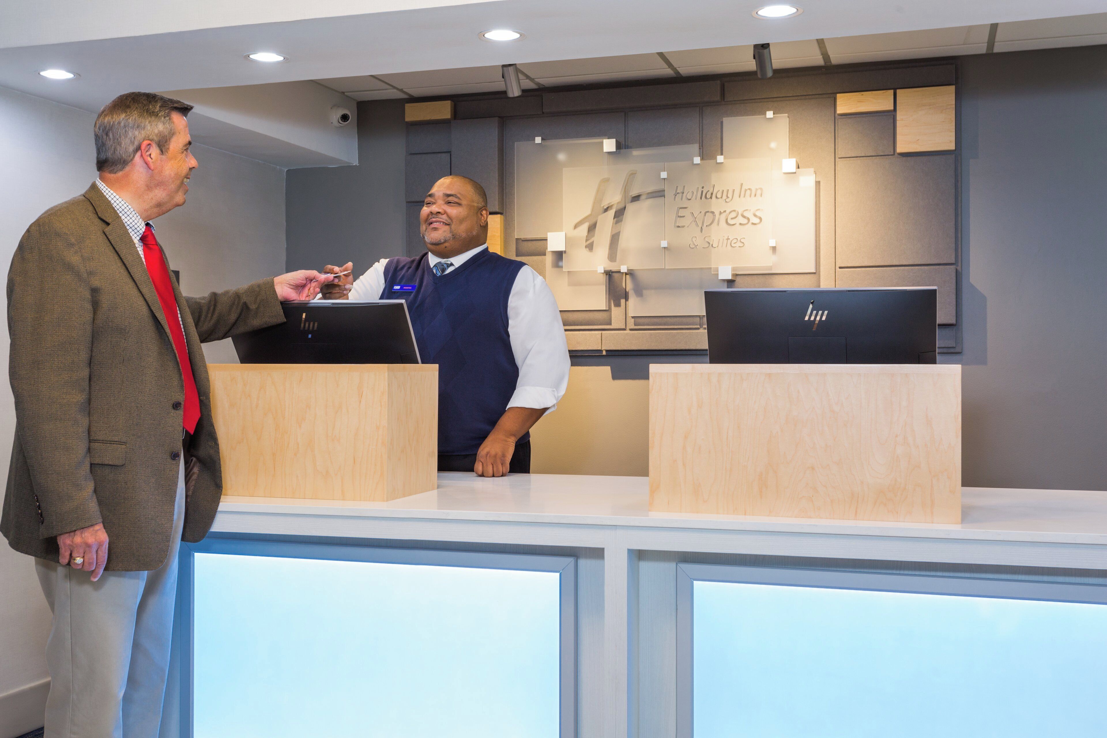 A reception desk with a sign indicating a Holiday Inn Express & Suites. There are two computer monitors on the desk.