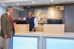 A reception desk with a sign indicating a Holiday Inn Express & Suites. There are two computer monitors on the desk. - Holiday Inn Express Hotel & Suites Wilmington-University Ctr by IHG (Wilmington)
