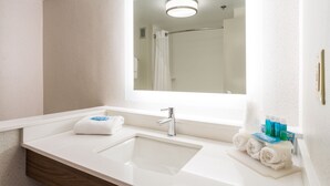 Un baño moderno con un espejo grande, un lavabo y una zona de ducha.