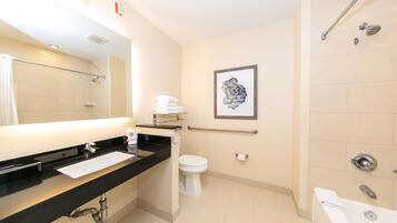 A modern bathroom with a black countertop sink, a white toilet, a framed artwork on the wall, and a shower area.