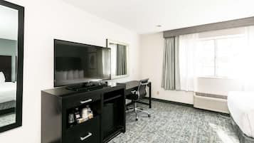 A hotel room with a bed, a desk with a chair, a television, and a wardrobe.