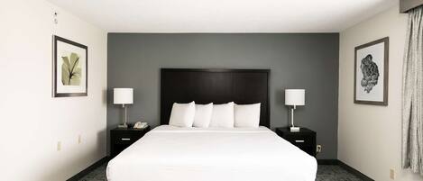A hotel room with a large bed, two bedside tables, and framed artwork on the walls.