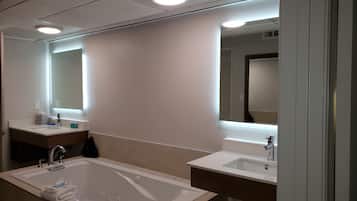 A modern bathroom with a large bathtub, two sinks, and a mirror.