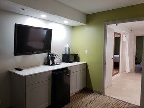 A compact kitchenette with a flat-screen TV, a coffee maker, and a microwave.