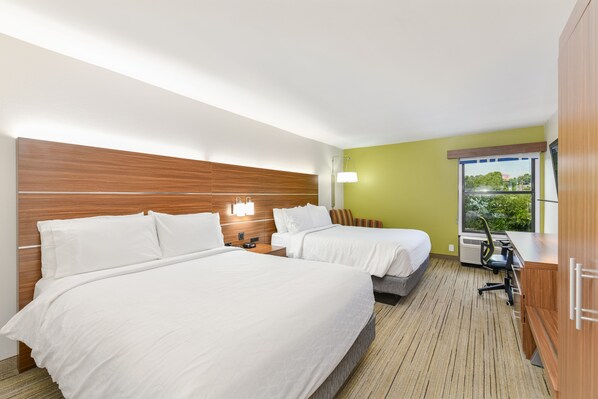 Une chambre d’hôtel avec deux lits, un bureau, une chaise, une lampe et une fenêtre donnant sur un beau paysage.