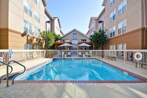 A swimming pool with a lifeguard station, lounge chairs, and a covered seating area.
