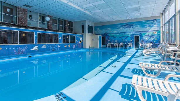 Una piscina interior con azulejos azules y un mural de una escena submarina.