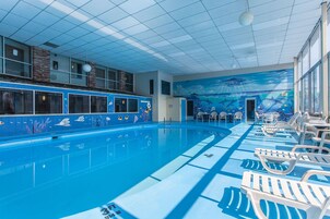 Una piscina interior con azulejos azules y un mural de una escena submarina.