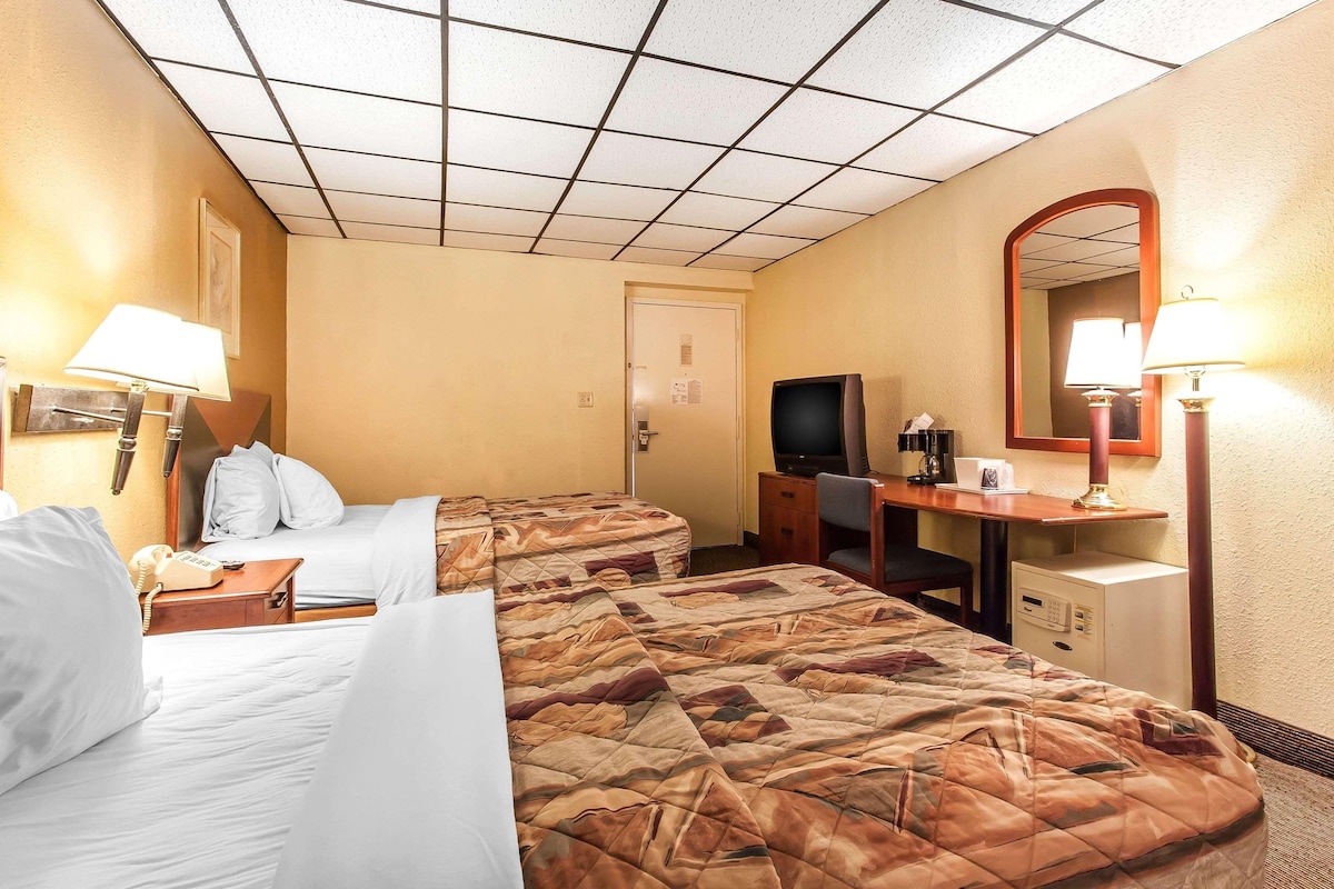 Habitación de hotel con dos camas, un escritorio, un televisor, un espejo y un teléfono.