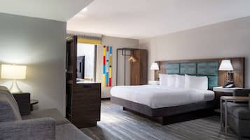 A hotel room with a large bed, a desk with a chair, a TV, and a wardrobe.