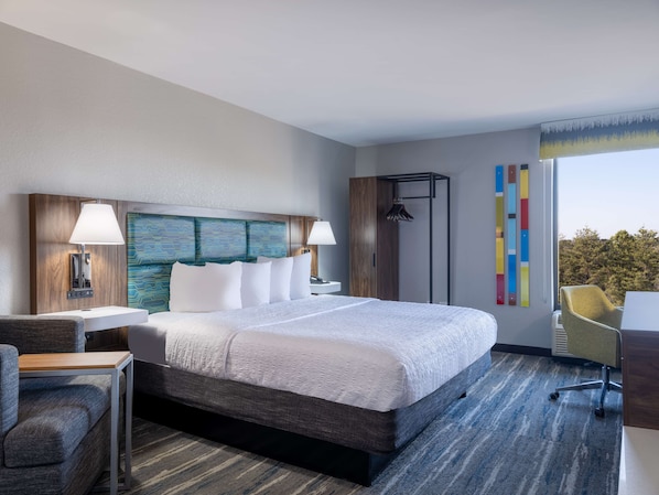 Una habitación de hotel moderna con una cama grande, un escritorio, una silla y un armario.