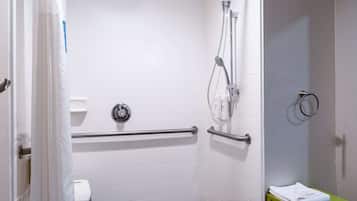 Un baño pequeño accesible con barra de apoyo, inodoro y taburete verde.