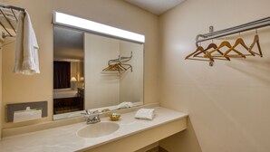 Een badkamer met een grote spiegel, een wastafel en een handdoekhouder.
