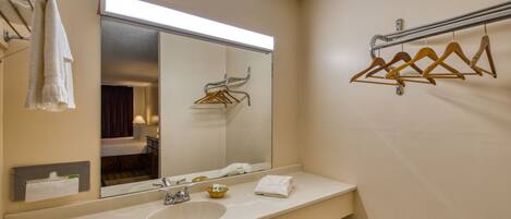 A bathroom with a large mirror, a sink, and a towel rack.