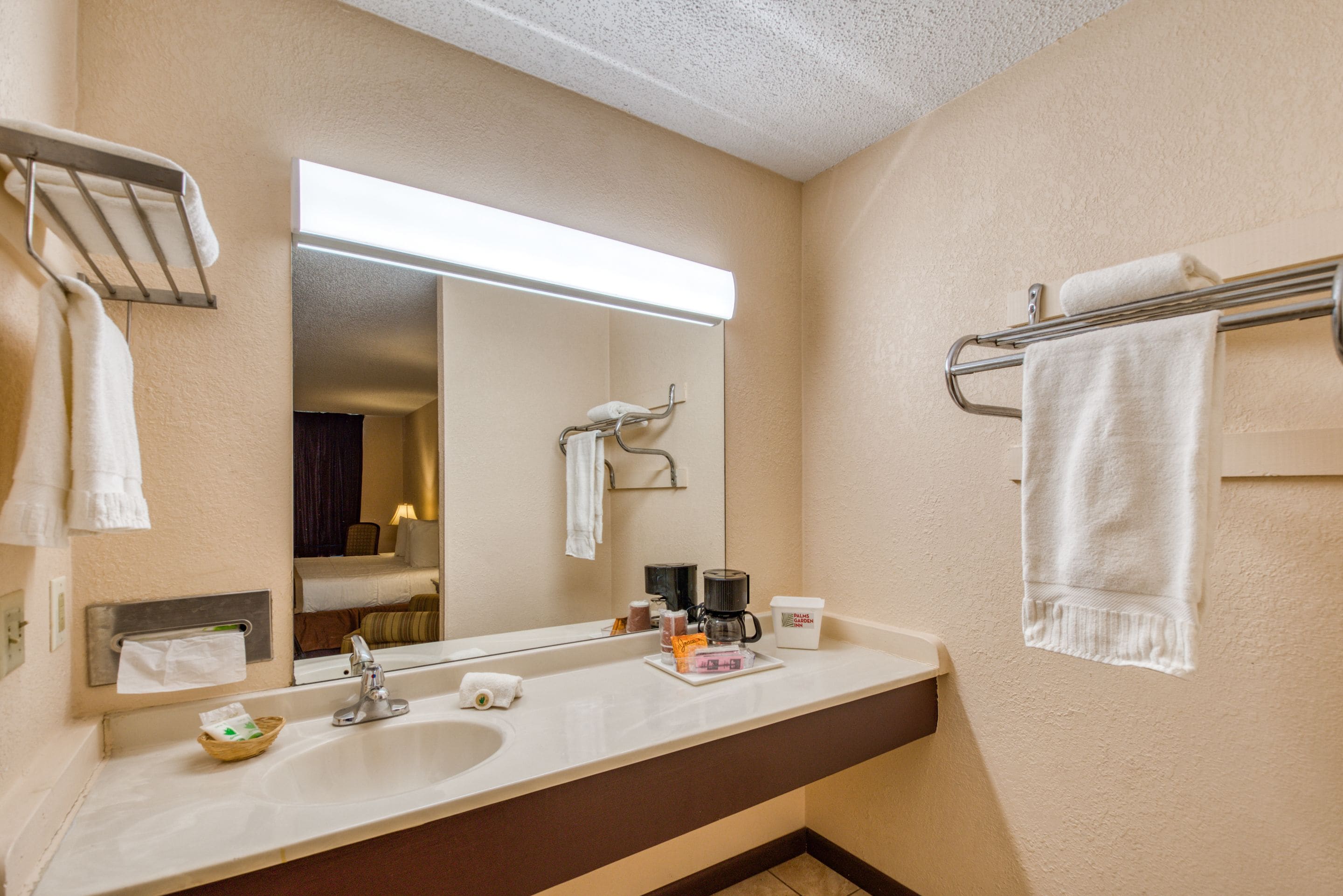 Een hotelbadkamer met een grote spiegel, een wastafel en handdoekhouders.