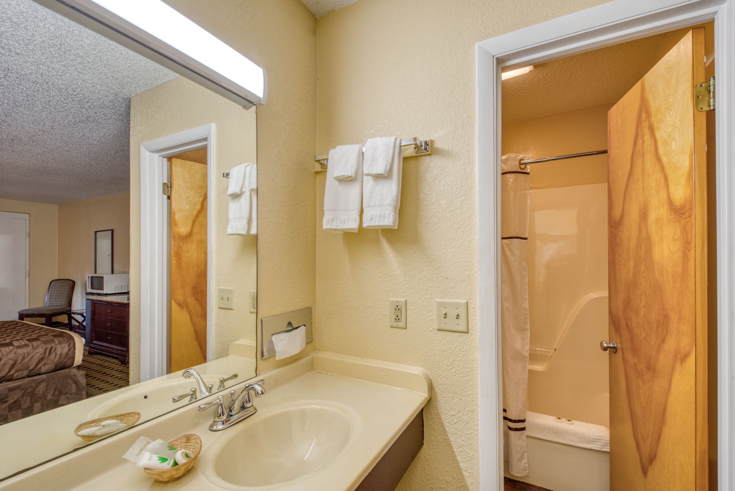 Un baño de hotel con lavamanos, espejo, toallero y zona de ducha.