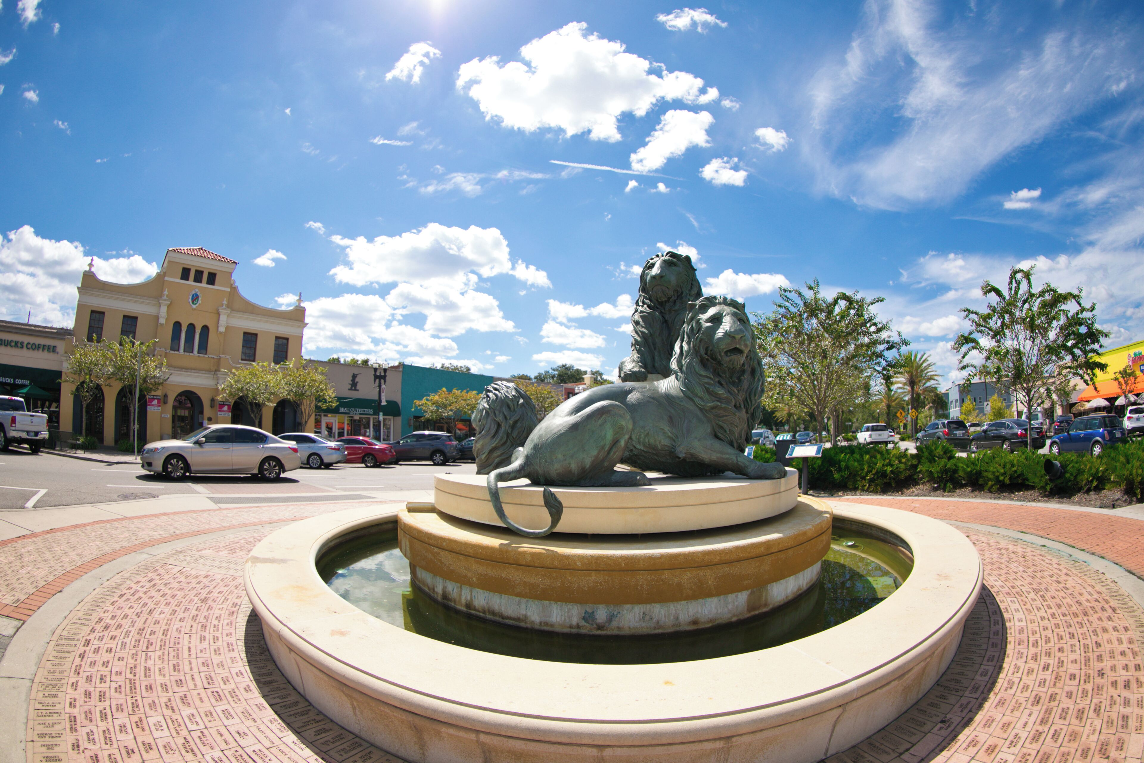 A fountain with two lion statues in the center, surrounded by a brick pathway.