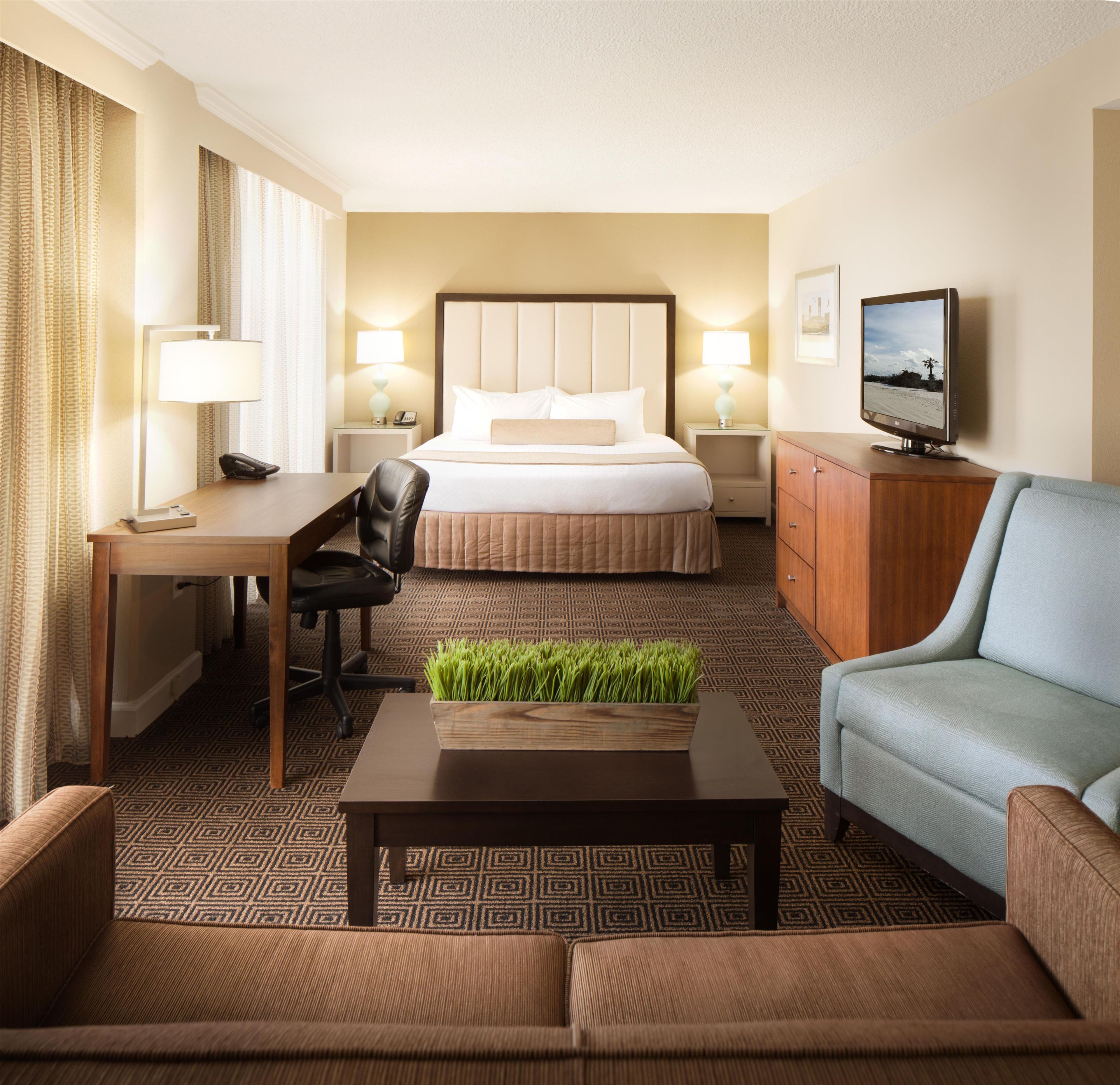Ein Hotelzimmer mit Bett, Schreibtisch, Fernseher, Sofa und Couchtisch.