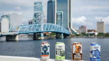 Four cans of beer with a city skyline and a bridge in the background.