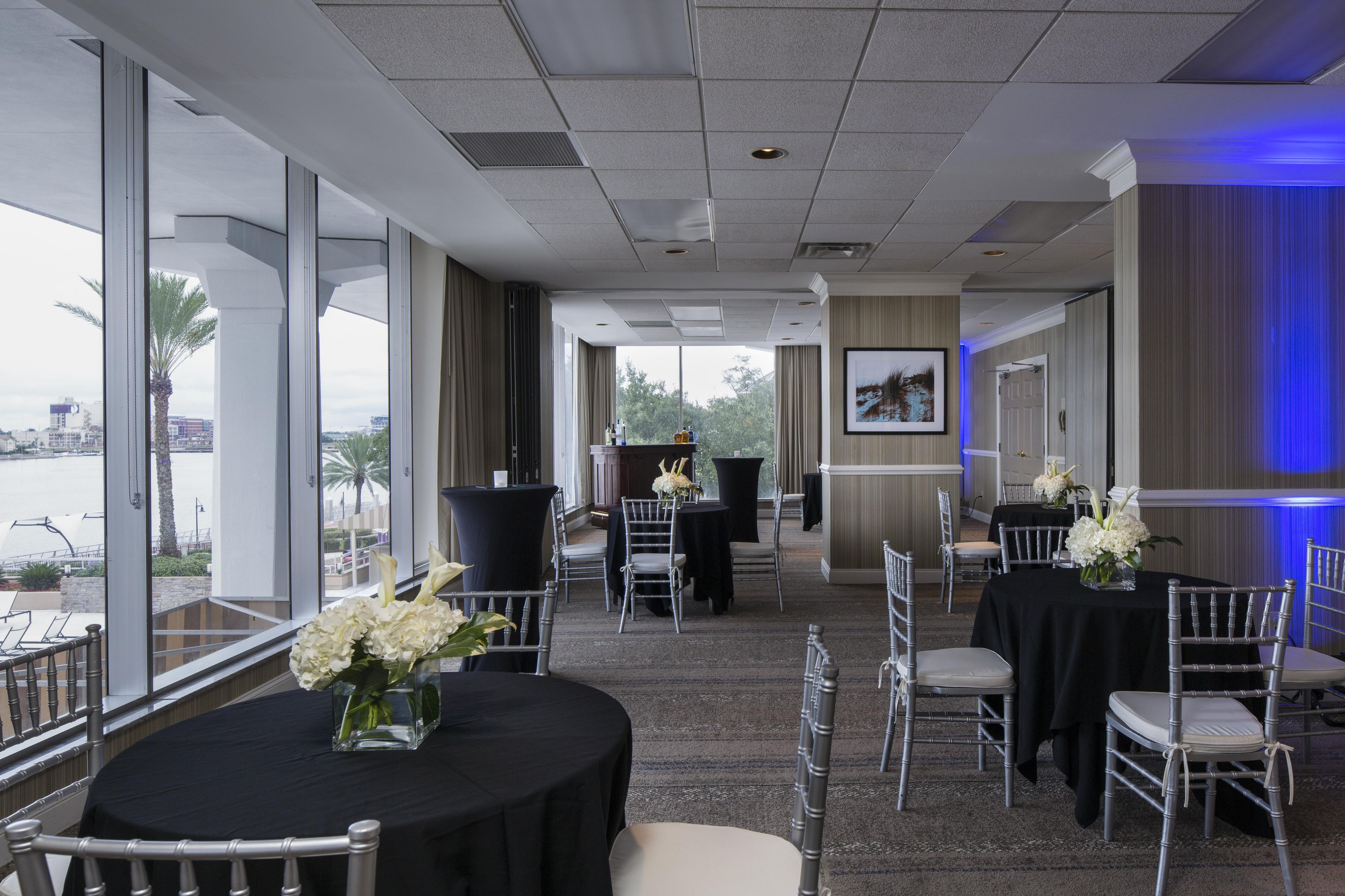 A conference room with tables and chairs, large windows, and a view of the outdoors.