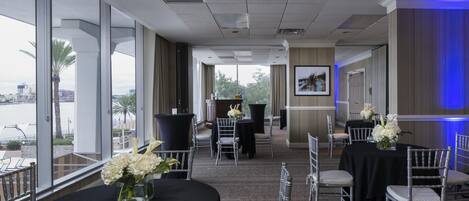 A conference room with tables and chairs, large windows, and a view of the outdoors.