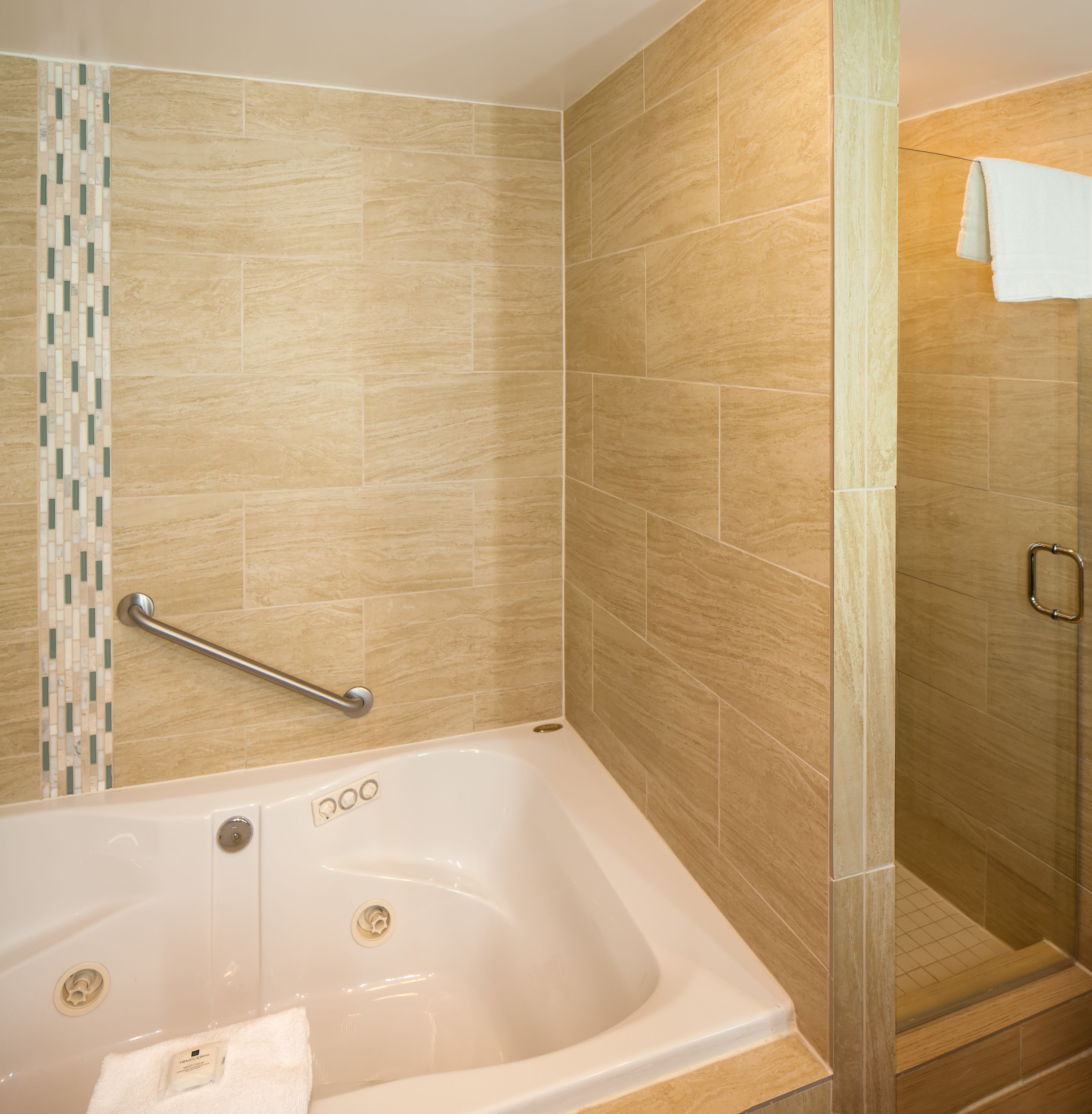 Un baño moderno con bañera, zona de ducha y barra de apoyo.