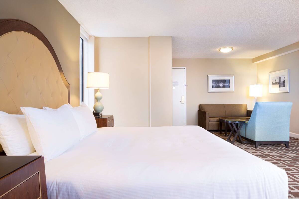 Une chambre d’hôtel avec un grand lit, un canapé, un fauteuil et deux lampes.