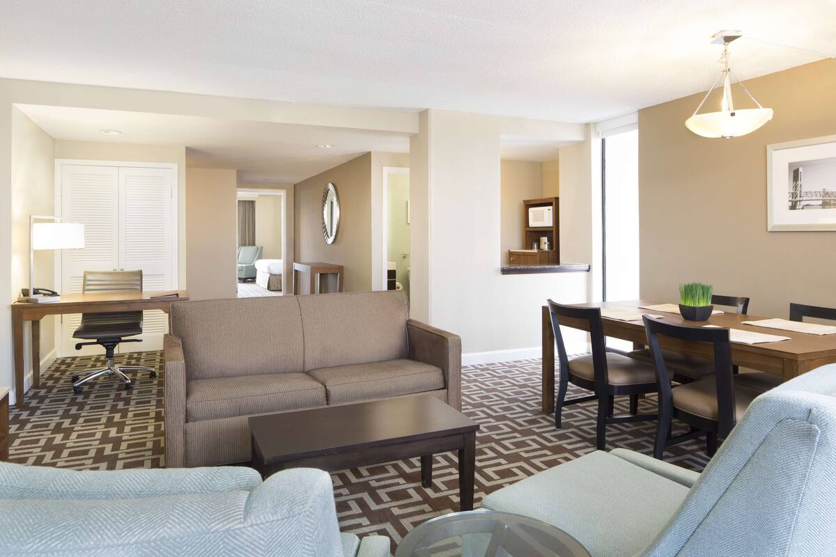 Une chambre d’hôtel comprenant un espace salon, un coin repas et une chambre à coucher séparée.