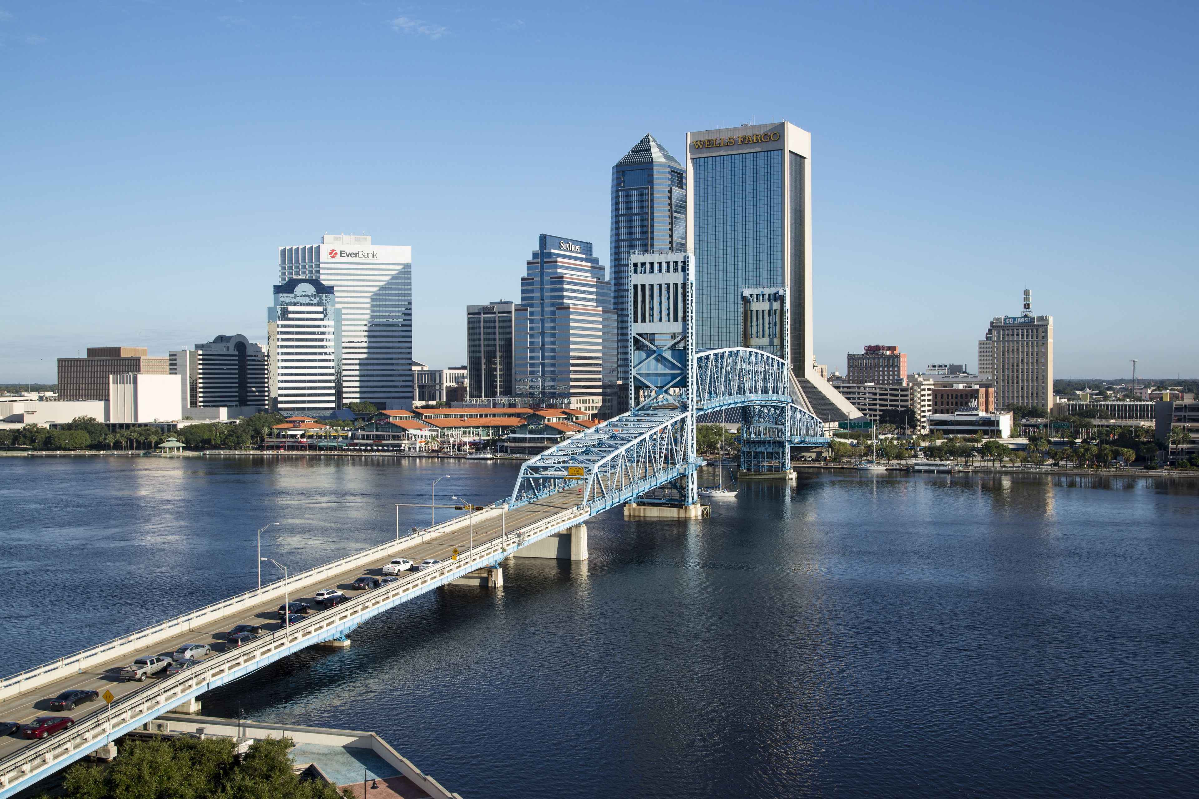 Stadsbeeld met moderne gebouwen, een opvallende brug en een rivier.