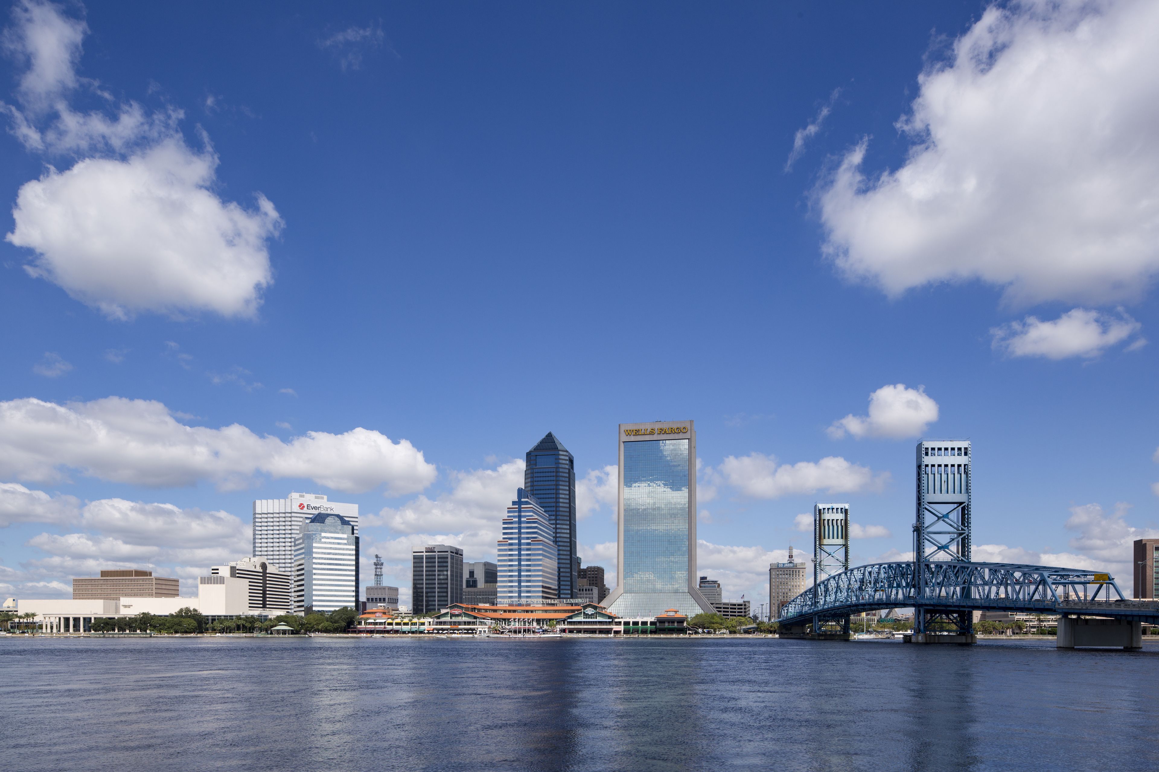 A city skyline with modern buildings and a bridge over a body of water.