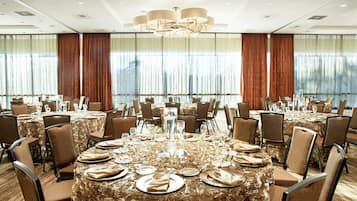 Un salón de banquetes con mesas redondas dispuestas para comer, equipado con sillas y vajilla.