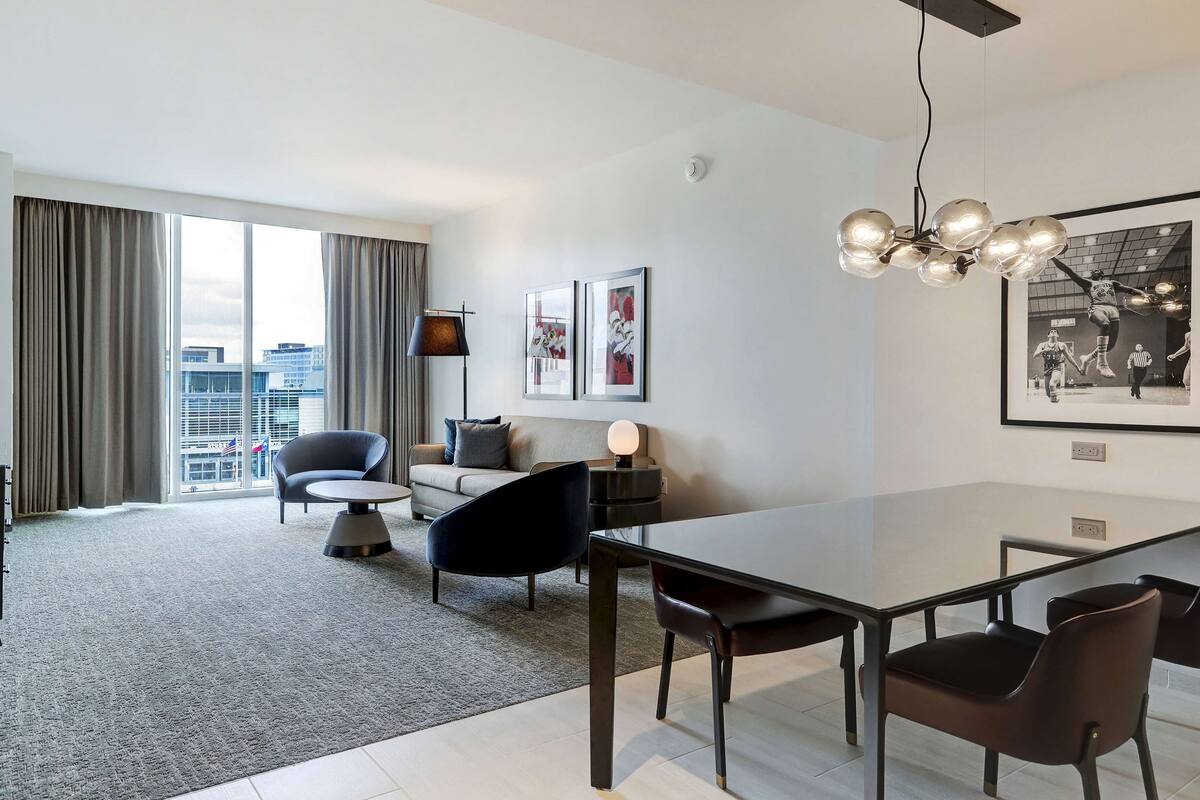 A modern living room with a dining area, large windows, and a city view.