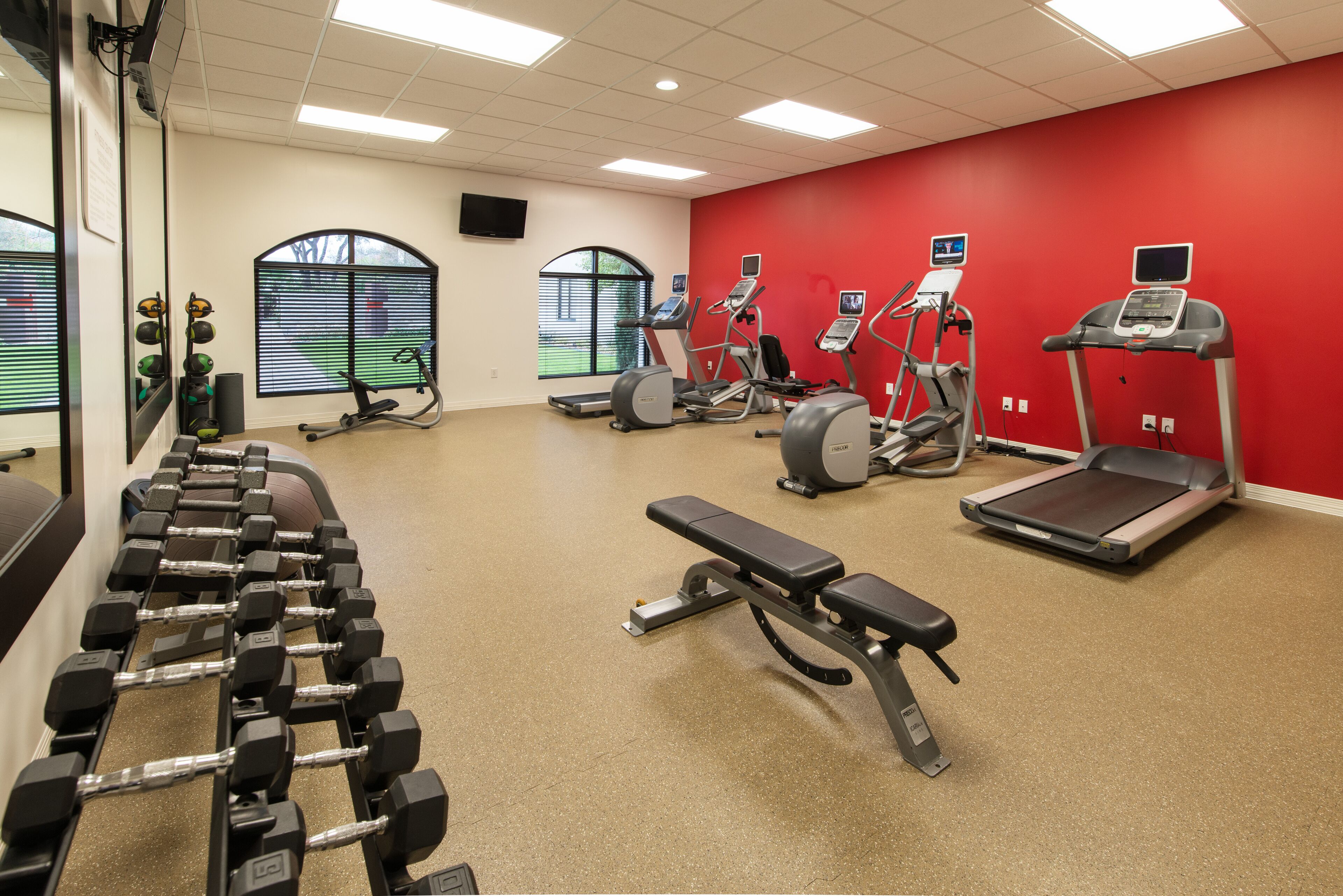 A gym with treadmills, elliptical machines, and a bench.