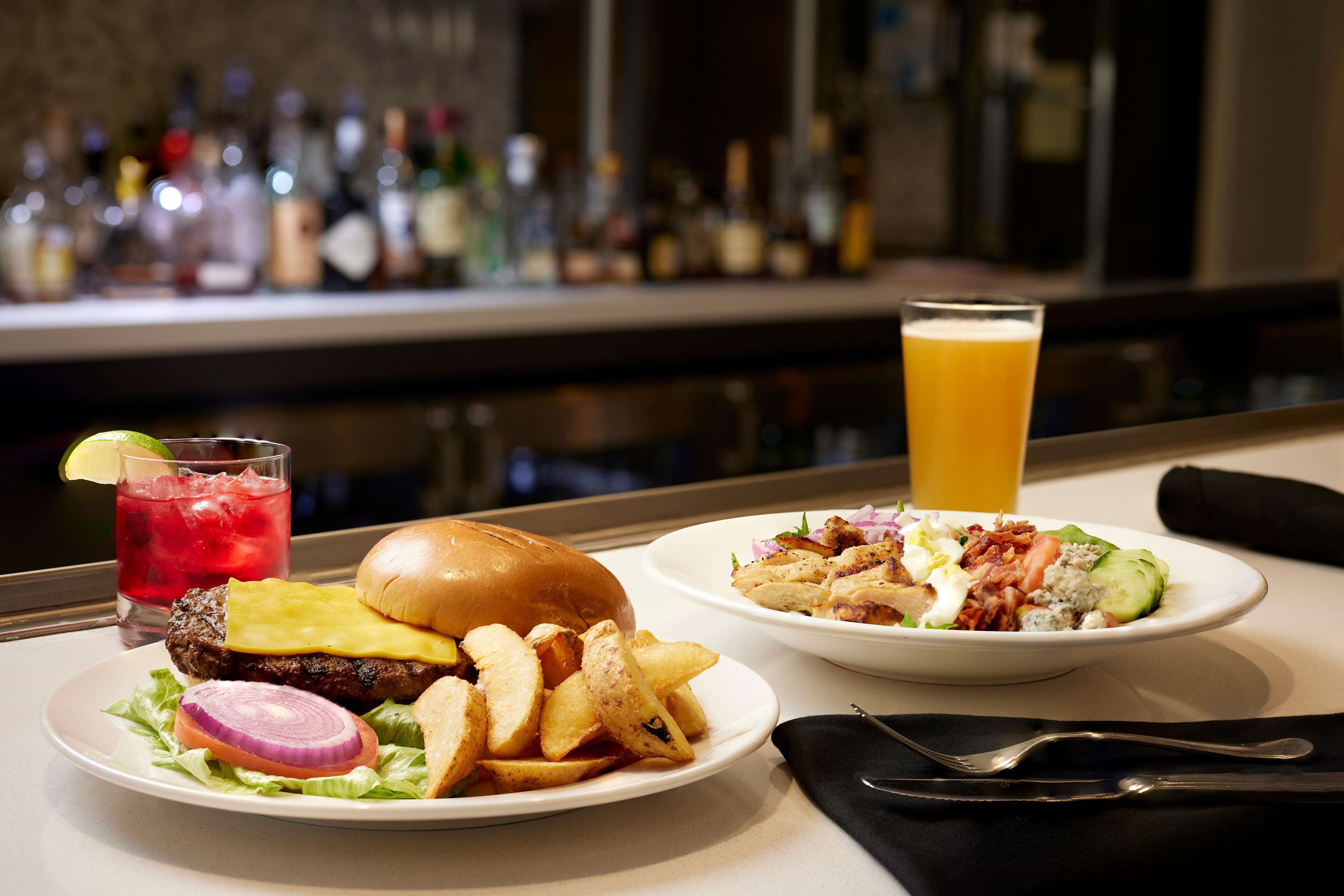 A meal with a burger, fries, and a salad, along with a drink and a glass of orange juice.