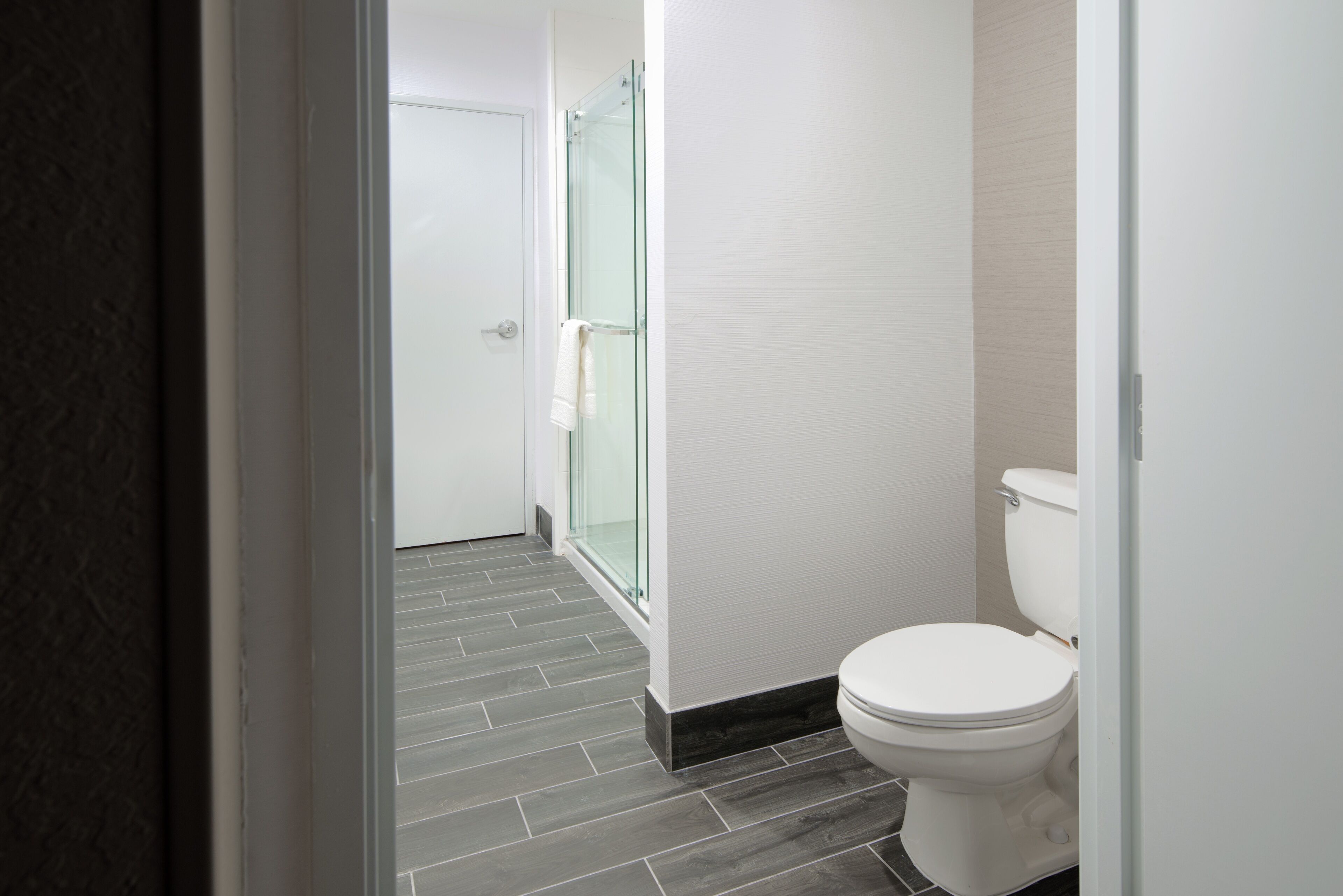 Un baño moderno con inodoro, cabina de ducha de vidrio y suelo de baldosas.
