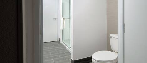 Un baño moderno con inodoro, cabina de ducha de vidrio y suelo de baldosas.