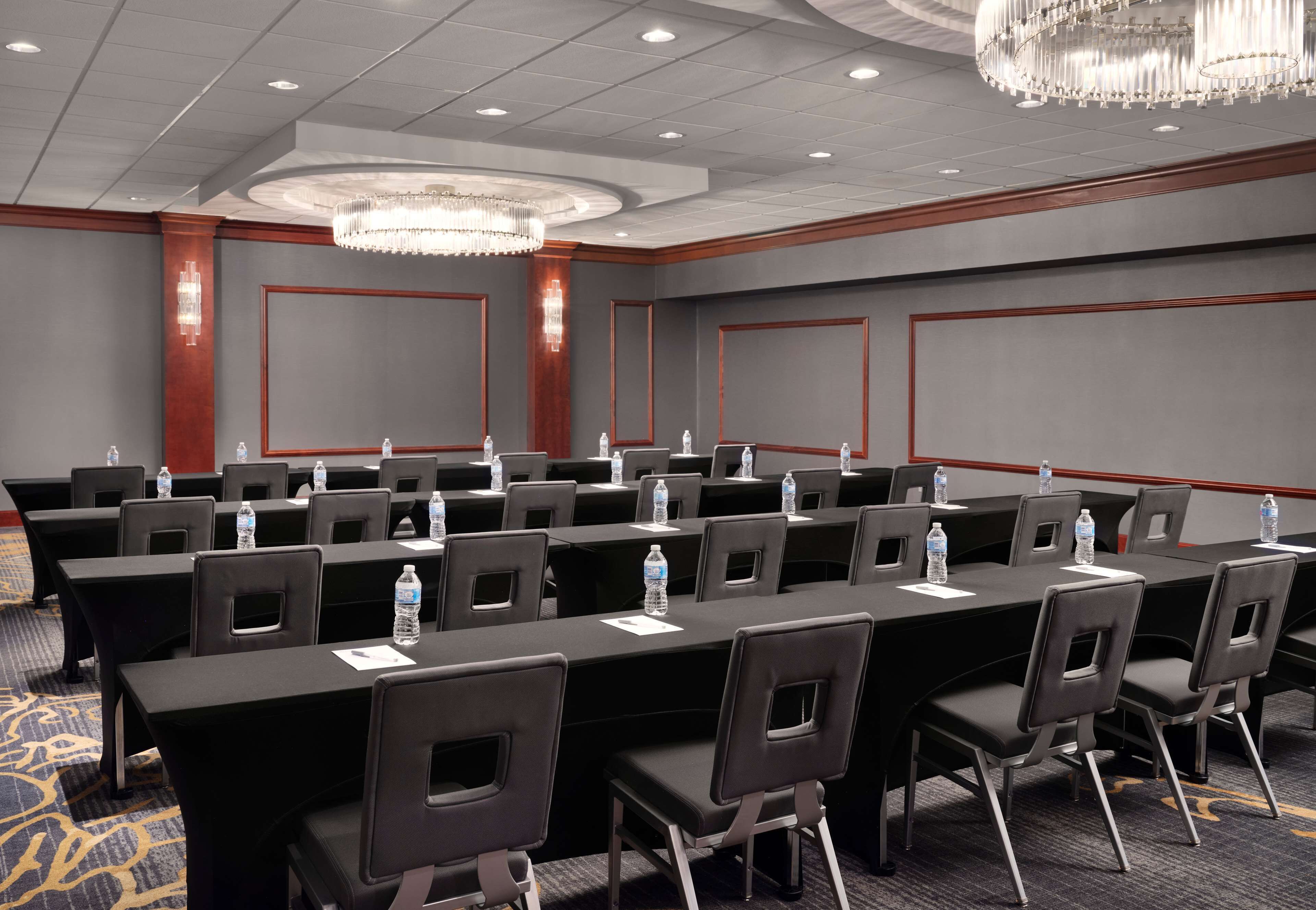 A conference room with multiple tables, chairs, and water bottles.