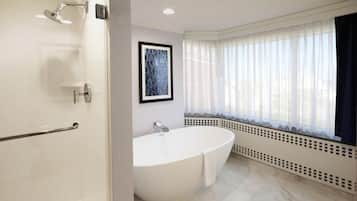 Une salle de bain moderne avec une baignoire sur pieds, une douche et une fenêtre ornée de rideaux légers.