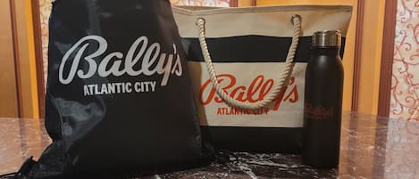 A black and a beige tote bag with "Bally's Atlantic City" printed on them, placed on a marble surface.
