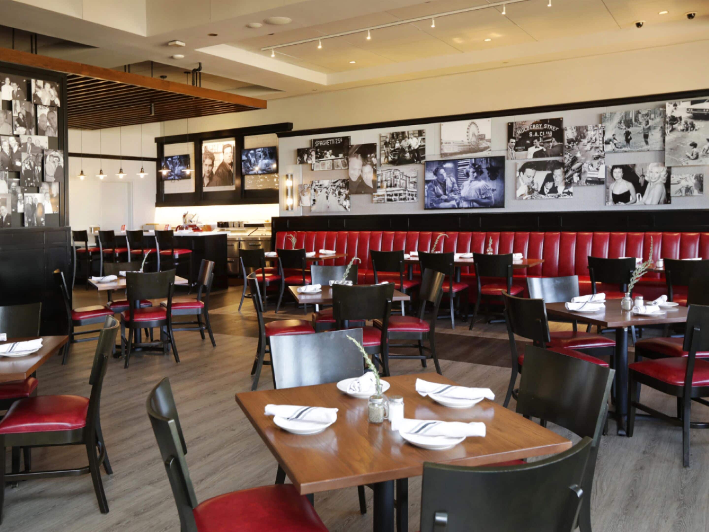 A restaurant with booths and tables, some with white napkins and silverware.
