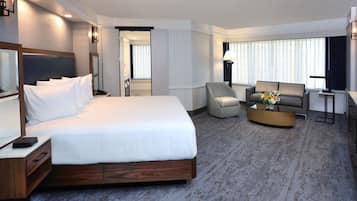 Une chambre d’hôtel dotée d’un grand lit, d’un coin salon avec un canapé et des fauteuils, d’une petite table basse et d’un téléviseur.