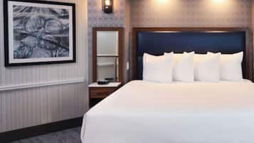 A hotel room with a large bed, a nightstand, a wall-mounted lamp, and a framed artwork.