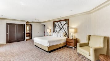 Habitación de hotel con una cama grande, una silla, una mesita de noche y un reloj de pared.
